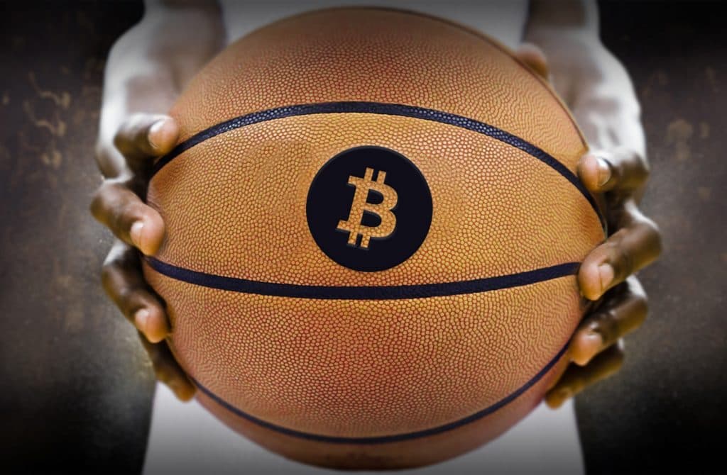 Man holding basketball with Bitcoin logo forward.