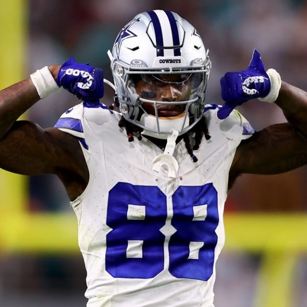NFL player dressed in blue and white gear showing muscles midfield.